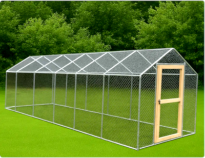 Large metal chicken coop with a wooden door on a grassy area with trees in the background