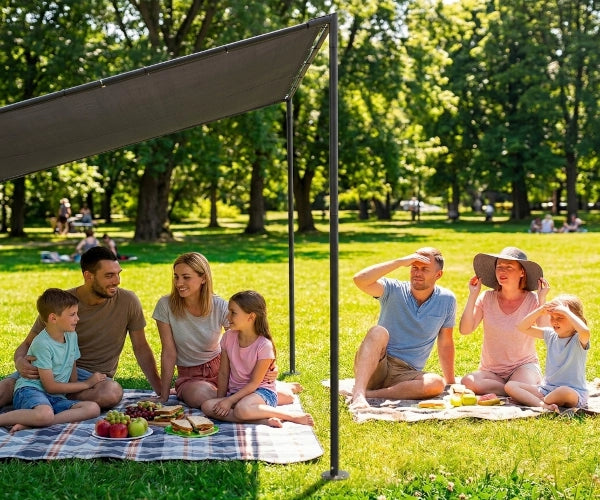 Family and friends enjoying a picnic under a canopy in a park.