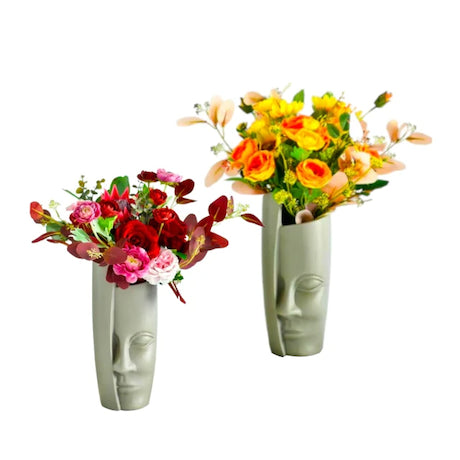 Two face-shaped vases with floral arrangements on a white background