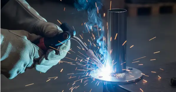 Welding a metal cylinder to base of footpad with sparks flying