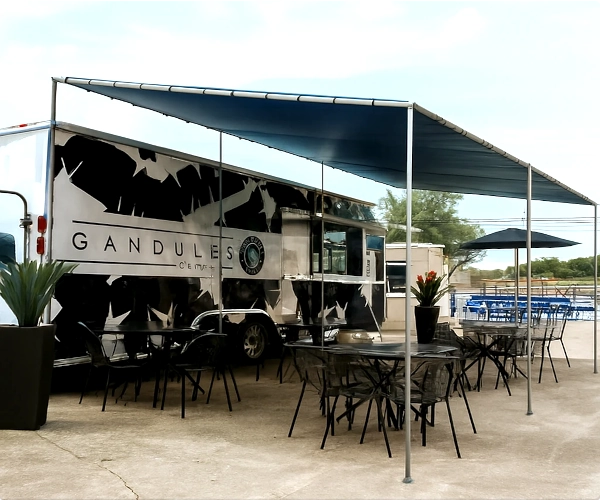 Slant-roof shelter, food truck with outdoor seating area on a clear day